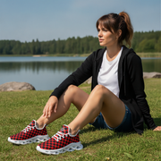 Woman sitting on grass by a lake wearing red checkered sneakers.