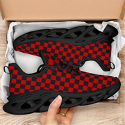 Red and black checkered sneaker with a hand holding it above an open cardboard box.
