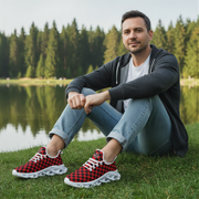 Man sitting by a lake wearing red and black checkered sneakers