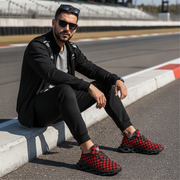 Man sitting on a race track wearing black and red checkered shoes