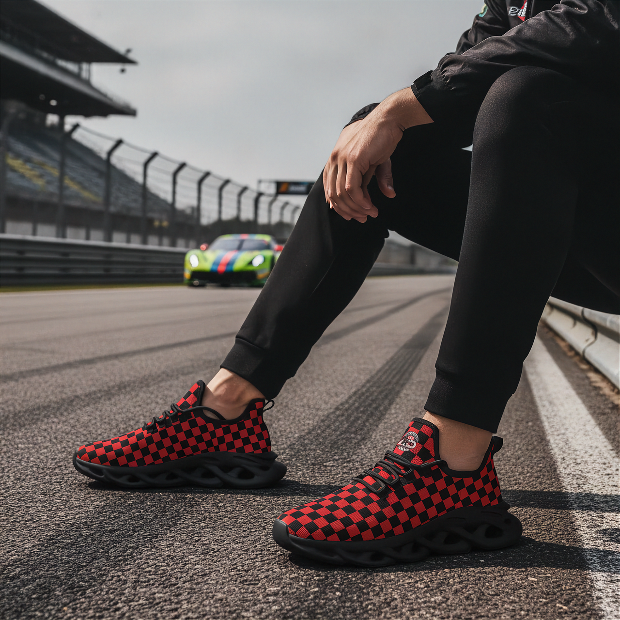 Man wearing red and black checkered shoes on a race track with a colorful car in the background.
