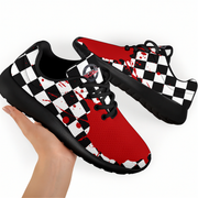 A pair of low-top sneakers with a black and white checkerboard pattern, red panels, and red splatter details, shown with one shoe being held by a hand against a white background.