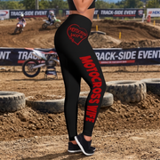 Black high-waisted leggings with red 'MOTOXROSS WIFE' text and a red heart logo on the back, shown on a model at a dirt motocross track.