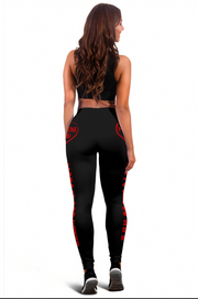 A woman shown from the back wearing black athletic leggings with red side graphics and a matching black sports bra, photographed against a plain white studio background.