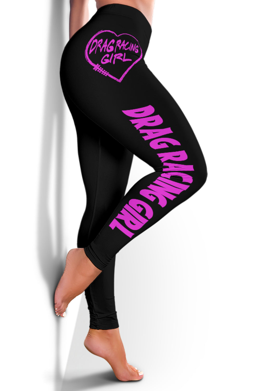 Side view of Drag Racing Girl leggings worn barefoot against a wall, with one knee bent to display the pink lettering.⠋