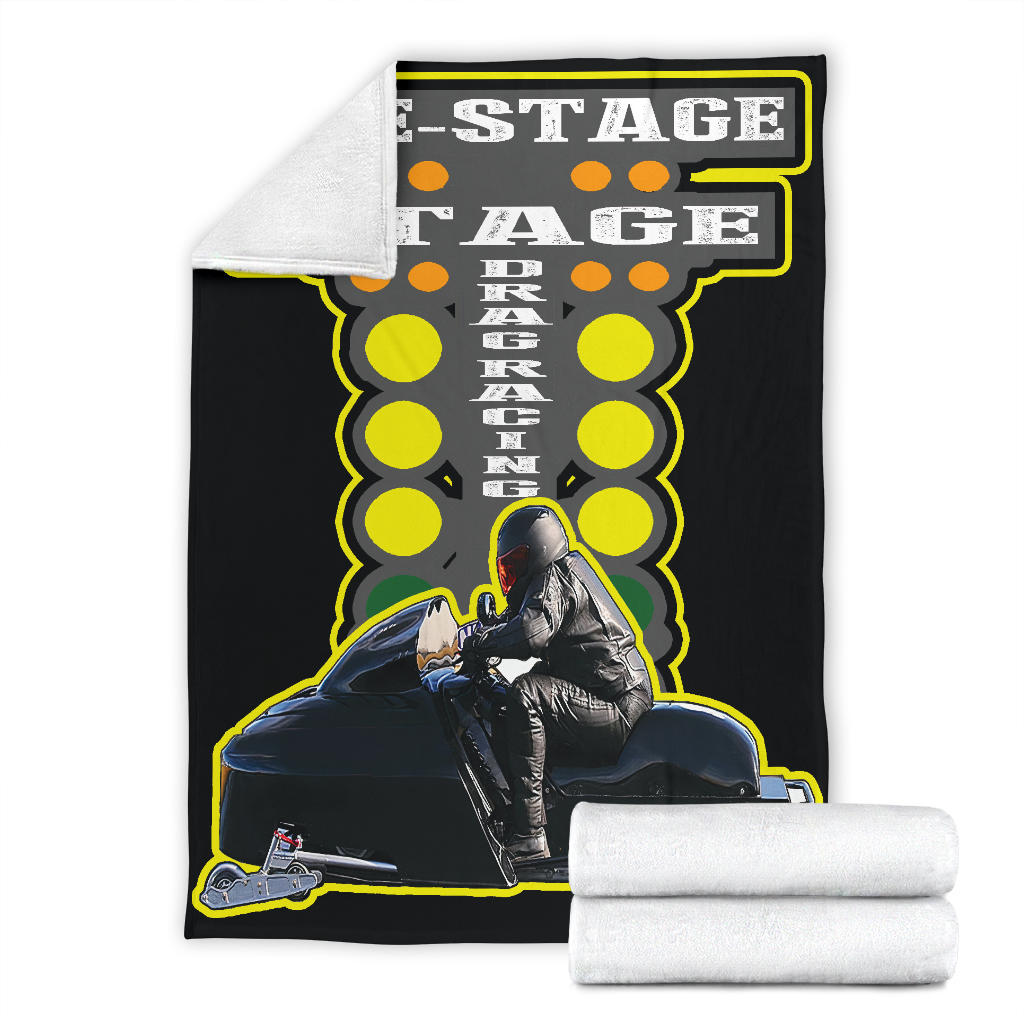 Snowmobile photo blanket displayed flat with a corner turned back to show white microfleece backing, beside folded blankets.