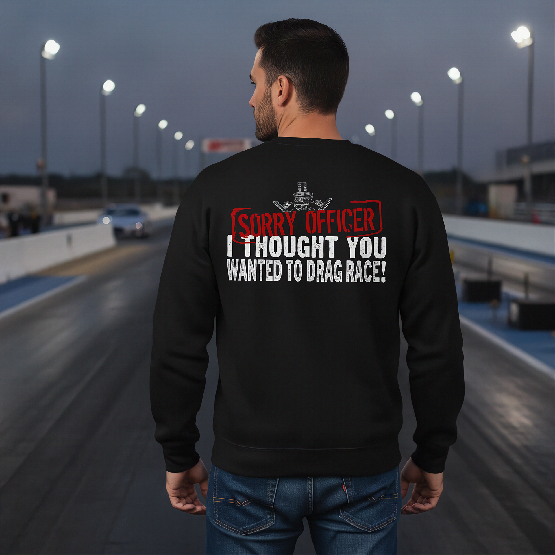 Man wearing a black sweatshirt with humorous drag racing quote text on a race track