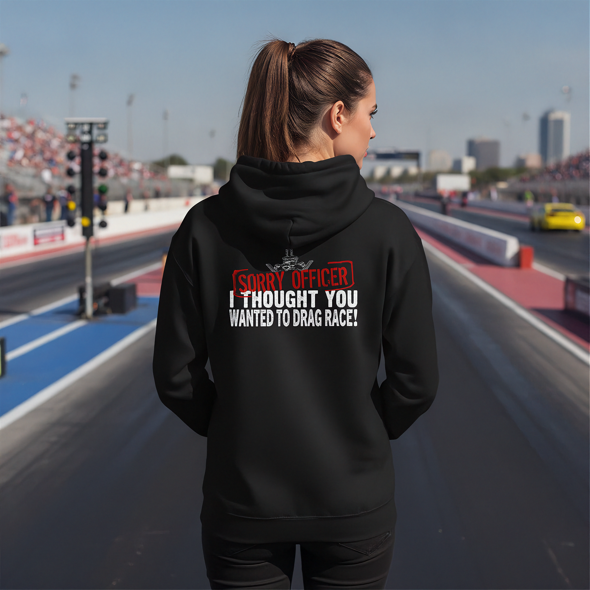  wearing a black hoodie with humorous drag racing quote text on a race track