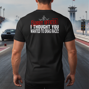 Man wearing a black t-shirt with humorous drag racing text on a race track background