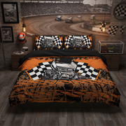 A racing-themed bedding set displayed on a bed in a styled bedroom. The set includes a duvet cover and two matching pillowcases featuring a hot rod race car graphic over a black-and-orange checkered flag design, set against a dirt track racetrack background.