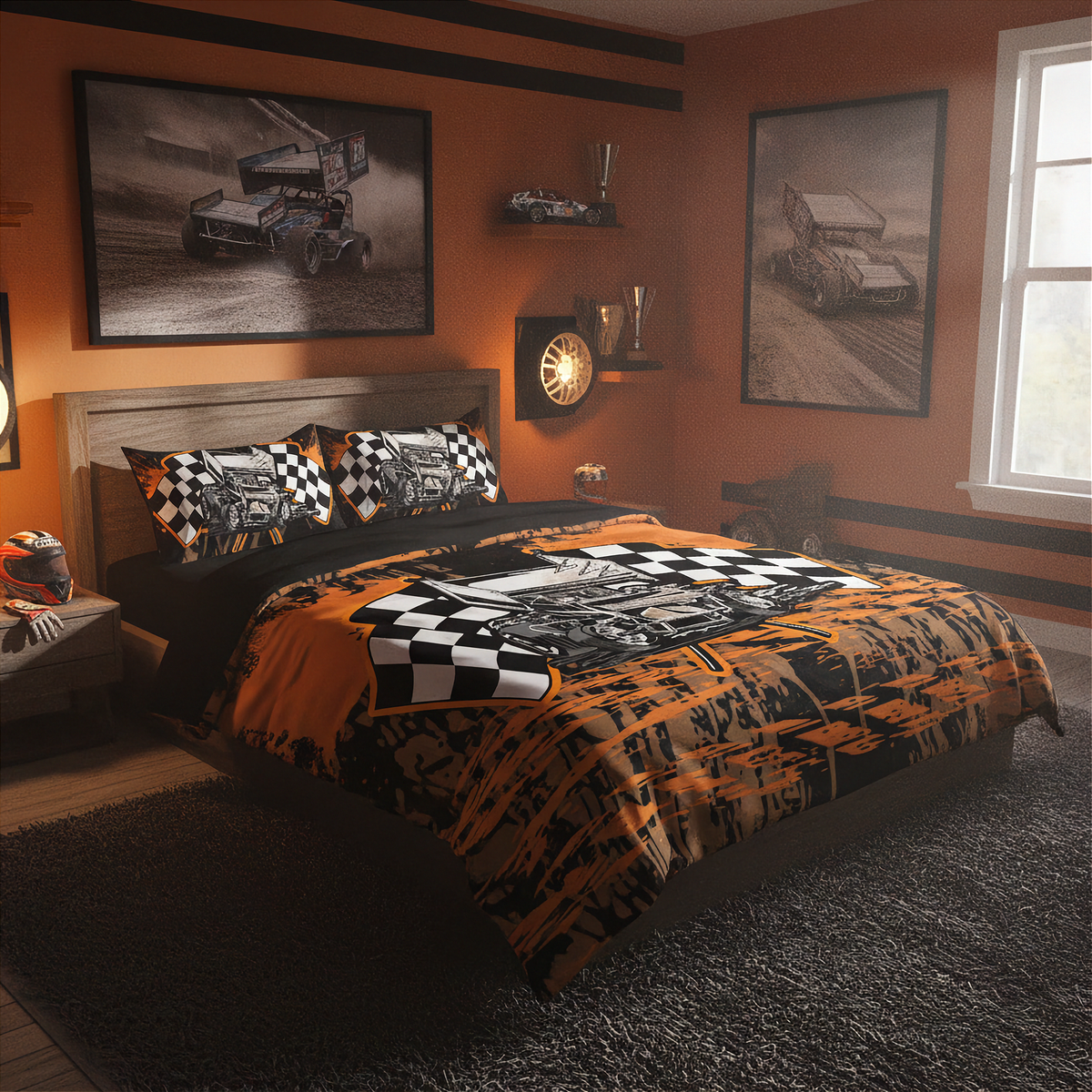 A racing-themed bedding set displayed on a bed in a styled bedroom. The set features a duvet cover and matching pillowcases with a bold black and orange paint-splatter design, checkered flag patterns, and illustrations of race cars.