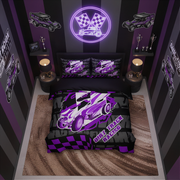 A racing-themed bedding set displayed on a bed in a styled bedroom. The set includes a duvet cover and two pillowcases featuring a purple and white race car graphic over a black and purple checkered pattern, with the text 'DIRT TRACK RACING'.
