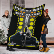 Two women displaying a custom snowmobile drag racing blanket outside a snowy porch, with the sample sled photo below the staging lights.