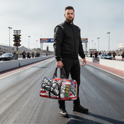 Man holding a usa themed drag racing duffel bag on a race track