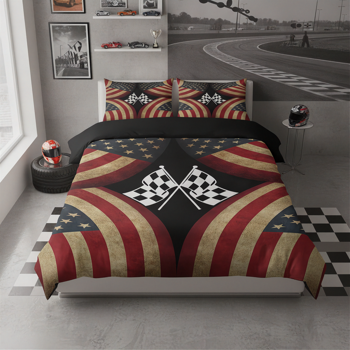 A racing-themed bedding set featuring a duvet cover and two matching pillowcases with a distressed American flag pattern, crossed checkered flags, and red, white, and blue stripes. The bed is styled in a modern gray racing simulator themed bedroom with a checkered floor mat, a tire prop with a helmet, and a wall mural of a racetrack.