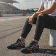 Woman sitting on a race track wearing black high-top shoes with racing design.