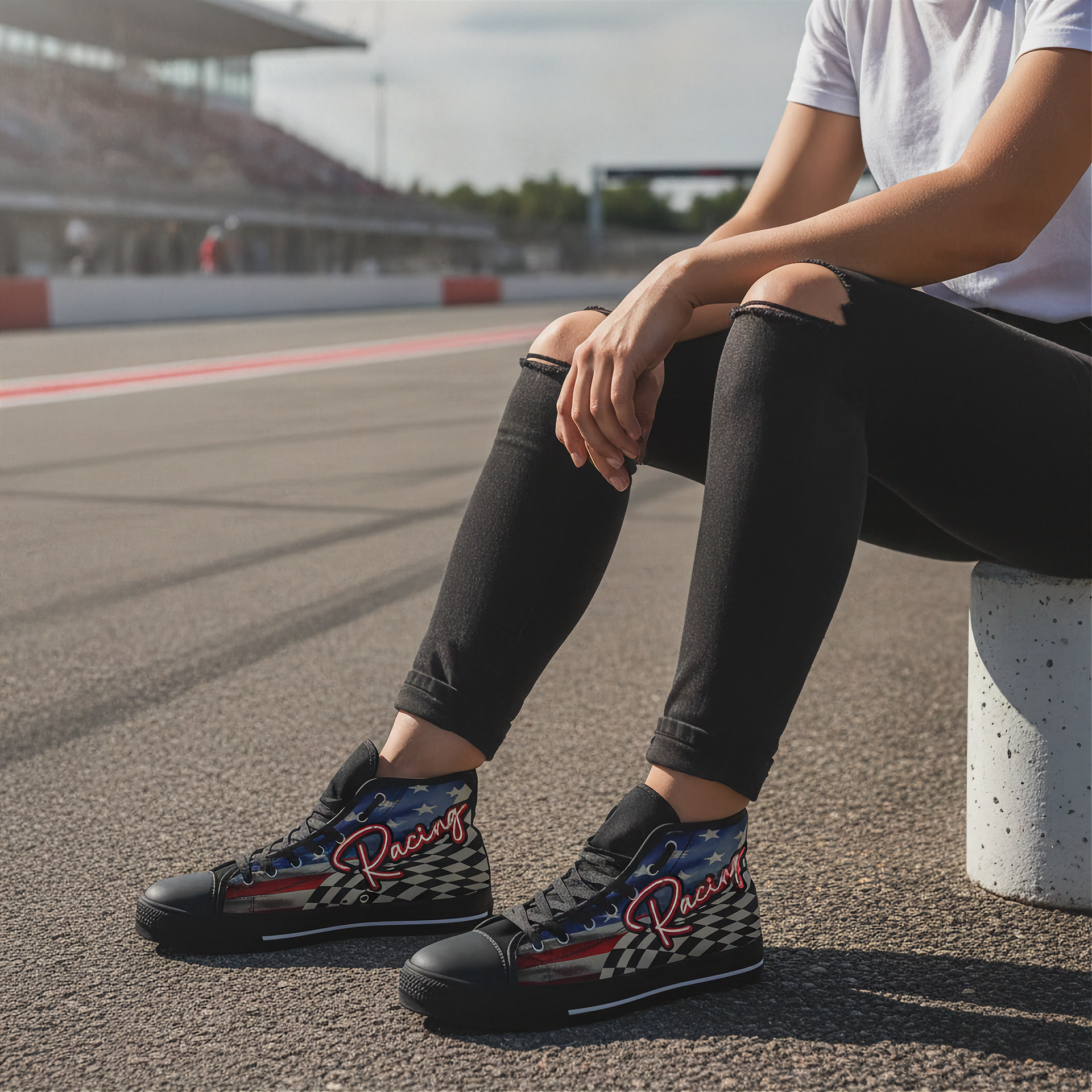 Woman sitting on a race track wearing black high-top shoes with racing design.
