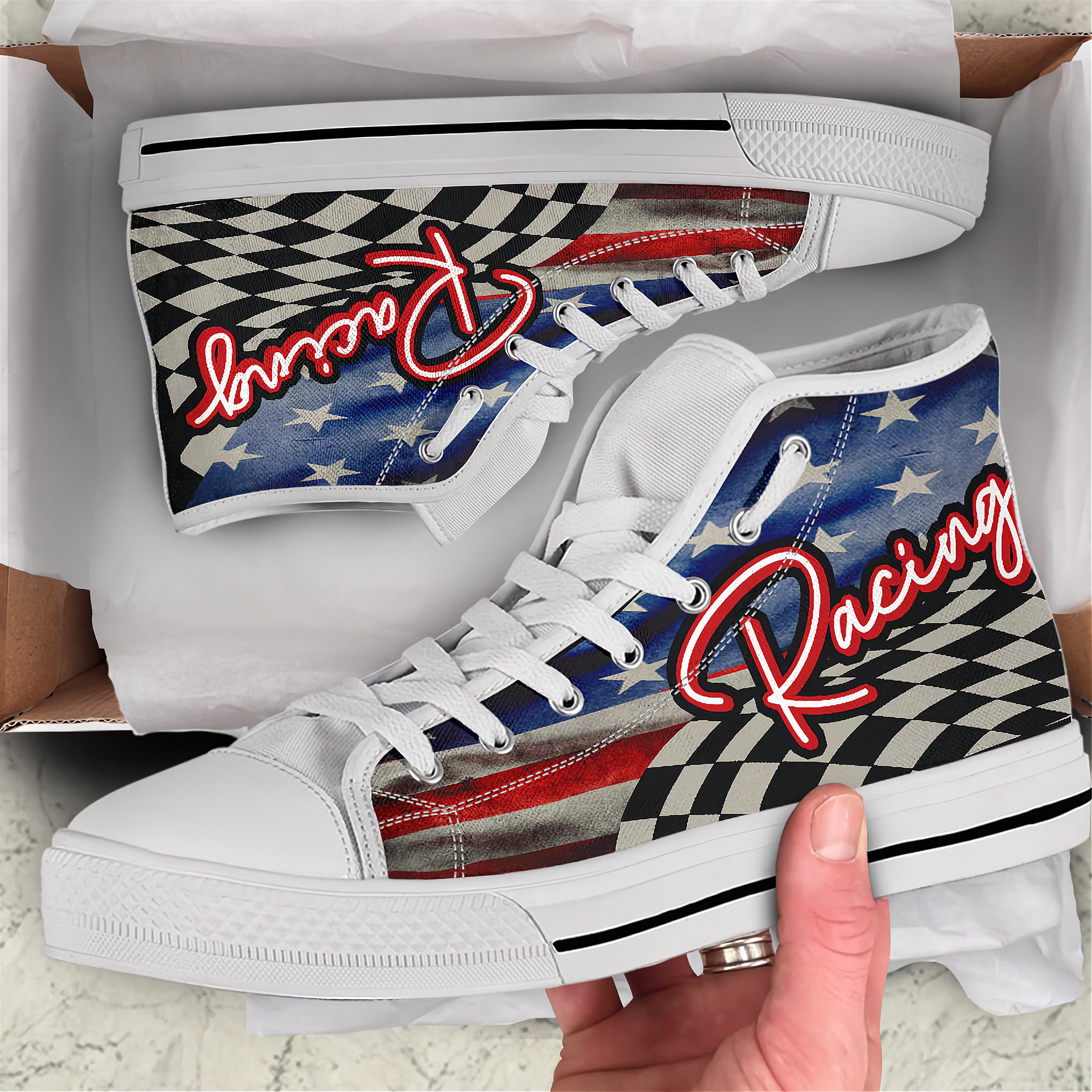 White high-top sneakers with racing design and text, held in a box.