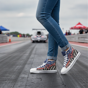 Person wearing checkered high-top sneakers on a race track with cars and tents in the background.