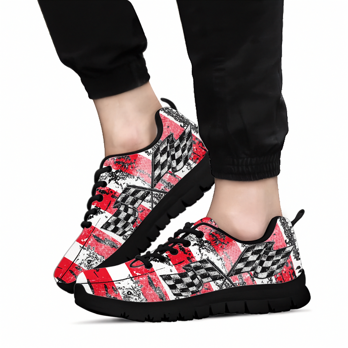 A pair of low-top sneakers with a vibrant, multicolored paisley and floral pattern in pink, purple, green, and blue, worn with black jogger pants against a plain white background.