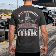 Man wearing a t-shirt with drag racing graphic and text at a race track.