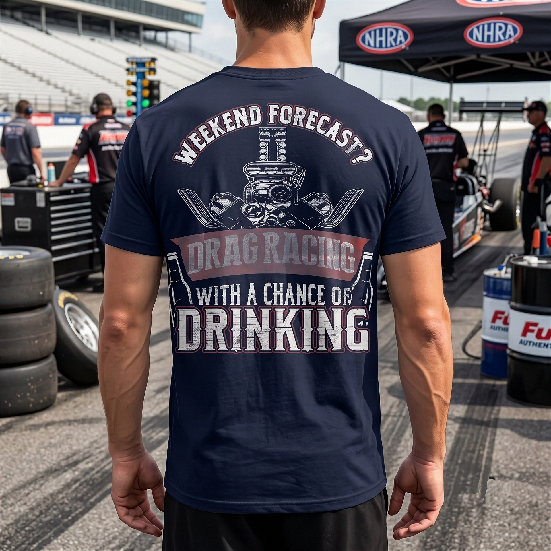 Person wearing a navy blue t-shirt with drag racing graphic and text at a race track.