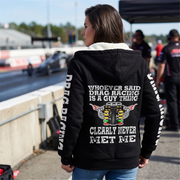 A woman modeling a black zip-up hoodie with a light beige fleece lining. The hoodie features a white graphic print on the back and white DRAG RACING on the sleeves.