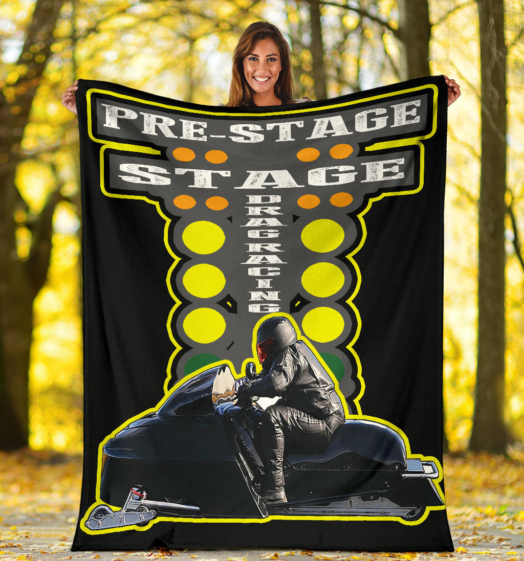 Woman holding a custom asphalt snowmobile blanket outdoors, showing a sample sled-and-rider photo beneath yellow-outlined drag starting lights.