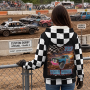 Woman watching demolition derby from behind a fence, wearing a jacket with personalized car, name, and number artwork.