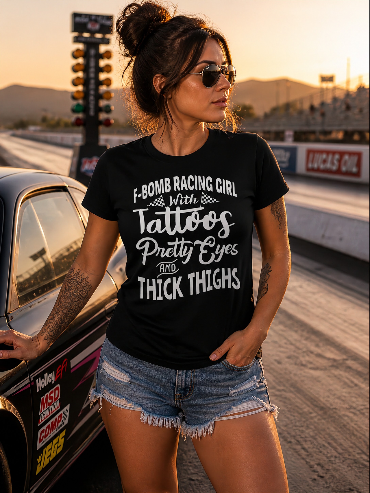 Women's F-Bomb Racing graphic apparel featuring the bold "Girl With Tattoos, Pretty Eyes, And Thick Thighs" slogan available in t-shirts, racerback tanks, and hoodies.