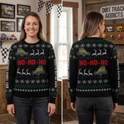 A split-view photo showing a woman modeling a black Christmas sweater indoors, with the front view on the left and back view on the right. The sweater has a holiday pattern with green and white snowflakes, white reindeer silhouettes, yellow and green off-road vehicles, and large red 'HO-HO-HO' text across the chest.