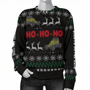A black Christmas crewneck sweater with a festive knit pattern featuring red 'HO-HO-HO' text, white snowflakes, green zig-zag lines, and gray reindeer carrying yellow and blue cargo. The sweater is displayed on a headless mannequin torso against a plain white background.