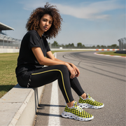 Woman sitting on a race track wearing black and yellow checkered sneakers.