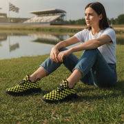 Woman sitting on grass wearing checkered shoes with a lake and stadium in the background