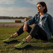 Woman sitting on grass wearing checkered shoes with a scenic background
