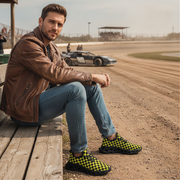 Man sitting on a wooden bench at a race track wearing checkered shoes.