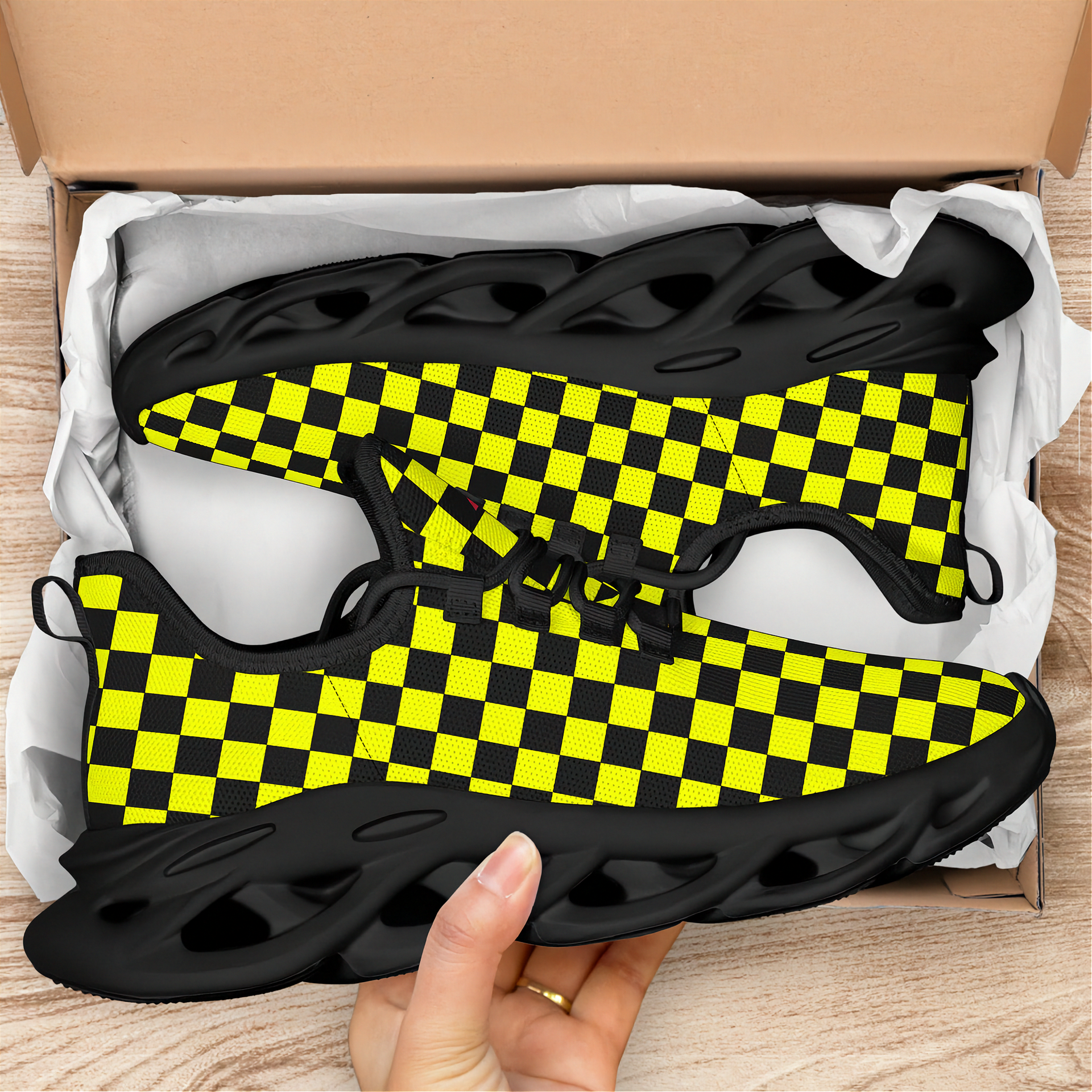 Black and yellow checkered sneakers in an open cardboard box on a wooden surface.