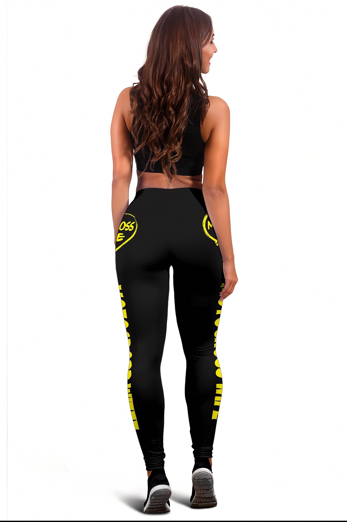 A woman shown from the back wearing black athletic leggings with bright yellow graphic text down the legs and a matching black sports bra, against a plain white background.