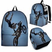A premium off-road motocross backpack featuring an artistic silhouette graphic of a dirt bike rider executing a massive freestyle whip, complete with heavy-duty black hardware, padded ergonomic shoulder straps, and a front utility pocket, isolated against a pristine white background.