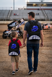 A vibrant royal blue custom racing backpack featuring an action illustration of a winged sprint car kicking up dirt, complete with thick padded black ergonomic shoulder straps and a front zipper pouch, isolated on a stark white background.