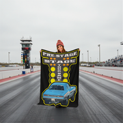 Person holding a custom drag racing  blanket with a race car design on a racetrack
