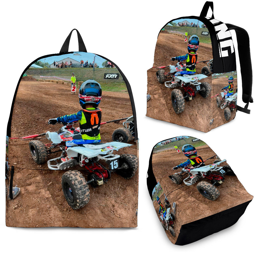 Custom personalized quad ATV backpack for kids featuring an off-road four-wheeler leaping over a muddy jump for back to school gear.