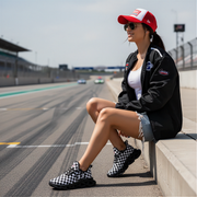 woman sitting at a race track wearing a back jacket with a custom checkered shoes number 33