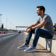 man sitting at a dragstrip wearing a grey t-shirt with a custom checkered shoes
