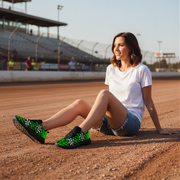 Woman sitting on a dirt track wearing green and black shoes