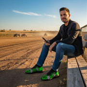 Man sitting on a wooden bench in an open field with green checkered shoes.