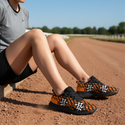 woman sitting on a dirt road wearing orange and black checkered shoes.