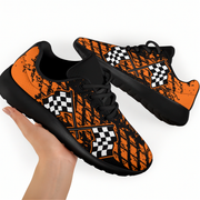 Orange and black sneakers with checkered pattern held by a hand on a white background