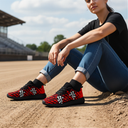 woman sitting on a baseball field wearing red and black dirt racing patterned shoes.