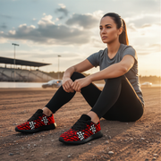 Woman sitting on a track wearing red and black checkered shoes at sunset.